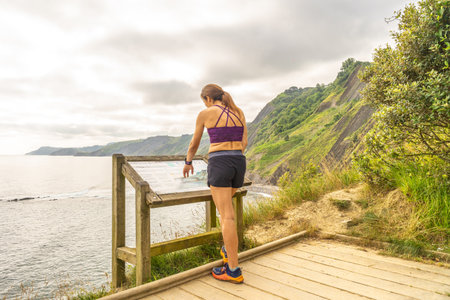 Female tourist consulting informative map at viewpoint in sakoneta beach, next to flysch in zumaia, basque country, spainの写真素材
