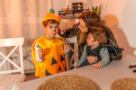 Mother painting her children's faces with halloween makeup, preparing for trick or treatingの写真素材