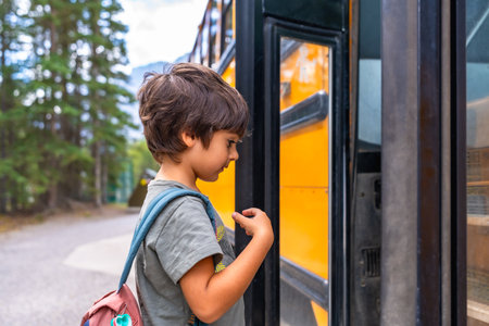 Curious preschool student with a backpack examines a yellow school bus before boarding, showing the anticipation and excitement of going back to schoolの写真素材
