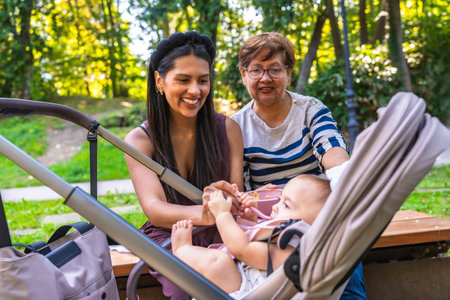 Grandmother, mother, and baby girl enjoying quality time together in a park, highlighting the joys...