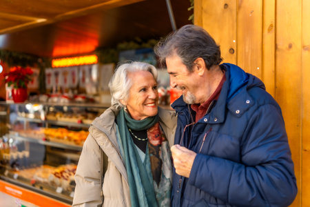 Happy senior couple smiling and enjoying time together during christmas holidays at a winter marketの写真素材