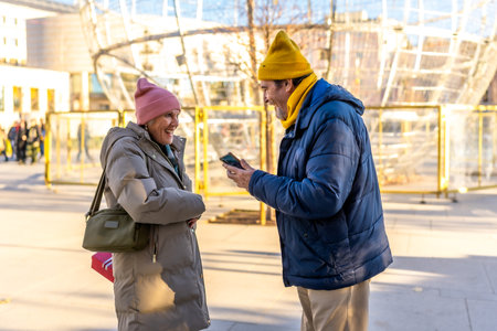 Elderly couple enjoying christmas time in a winter city, sharing a moment of joy with a smartphoneの写真素材