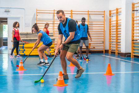 Group of athletes engaging in floorball practice, running with sticks and skillfully hitting the...