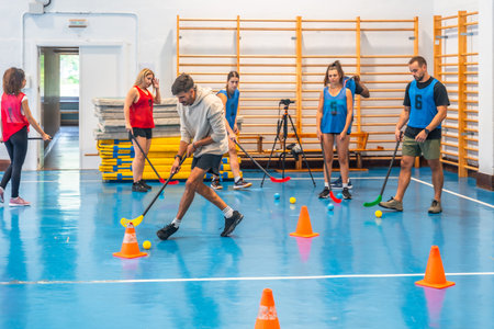 Group of athletes practicing floorball, passing the ball with sticks and maneuvering around cones in...