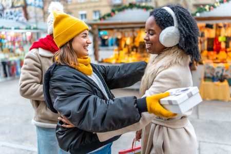 Two happy women exchanging Christmas gifts at a Christmas market, enjoying winter holidays togetherの写真素材