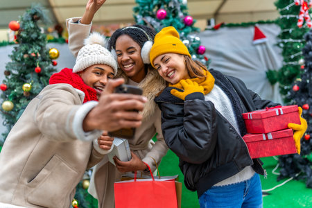 Happy multi ethnic friends taking a selfie after a Christmas shopping spree, holding gifts and...