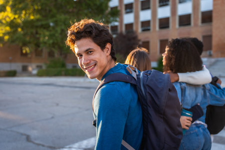 University student smiling at the camera with a backpack, walking with friends on campus, showing...