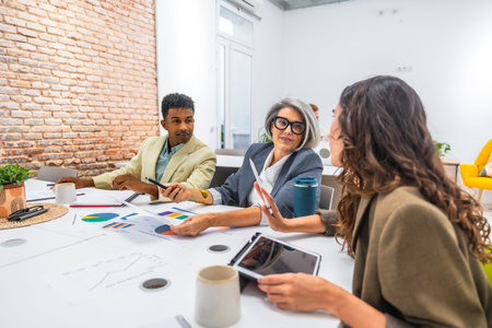 Diverse business professionals collaborating in a modern office. Analyzing data and discussing...