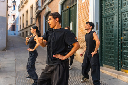 Young men and women in black clothing performing a synchronized dance routine on a cobblestone alley in a European city, expressing artistic freedom and urban cultureの写真素材