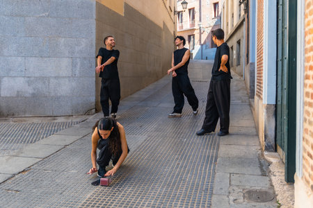 Group of young friends wearing black clothing rehearsing a contemporary dance routine on a...
