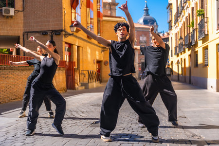Group of four youth street dancers dressed in black performing contemporary choreography in a...
