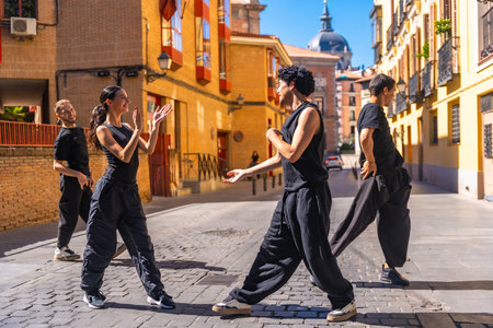 Dance troupe performing a contemporary routine on a cobblestone street, expressing passion and dynamic movement in an urban setting with historic architectureの写真素材