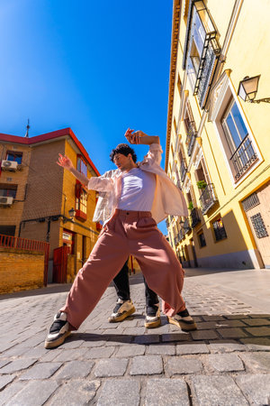 Young man actively dancing a contemporary urban street performance, expressing freedom and vibrant energy on a sunny day in an old city alley with traditional architectureの写真素材
