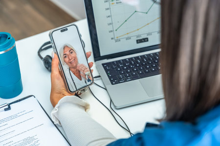 Woman having an online telemedicine consultation with a senior female doctor on a mobile phone, using technology for remote healthcare and patient care from homeの写真素材