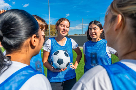 Women soccer players in blue uniforms huddled on a green field, smiling and planning strategy together before a game teamwork, focus, coaching and outdoor athletic preparationの写真素材