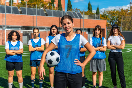 Confident young adult women soccer players standing together on the artificial grass football field, ready for training session, promoting female empowerment in sportsの写真素材