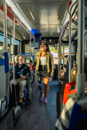 Young woman with a prosthetic leg confidently walking down the aisle of a public bus, representing concepts of inclusion, diversity, and accessible urban transportation for people with disabilitiesの写真素材