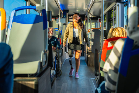 Young woman with a prosthetic leg confidently walking down a bright city bus aisle among seated passengers, embodying accessibility, independence and urban inclusionの写真素材