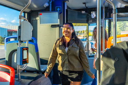 Woman smiling and walking inside a modern city bus, preparing for her daily commute, representing urban lifestyle, public transport convenience, and happy travel experienceの写真素材