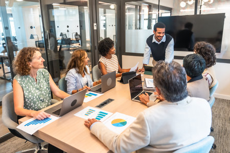 Diverse business professionals conducting a collaborative meeting in a modern office, analyzing data and discussing strategy, representing teamwork and corporate successの写真素材