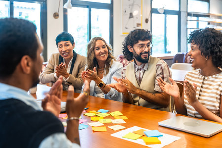 Coworkers clapping and smiling during a collaborative office meeting, showcasing teamwork, appreciation, and positive engagement in a modern coworking spaceの写真素材