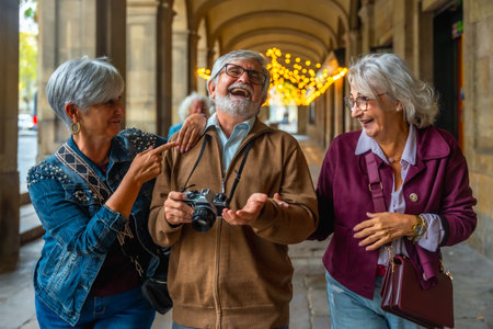 Group of excited senior friends enjoying their city trip, laughing and walking together in an arched arcade, sharing a happy and memorable travel momentの写真素材