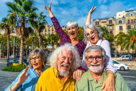 Happy senior friends smiling and raising hands, celebrating friendship and active retirement during a city vacation, conveying joy, togetherness, and a fulfilling lifestyleの写真素材