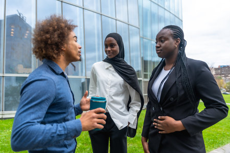 Diverse business professionals standing outdoors, engaging in an informal discussion during a break, demonstrating collaboration and teamwork in a modern urban environmentの写真素材
