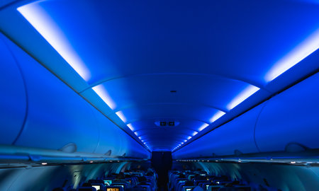 Blue cabin lights creating a relaxing atmosphere inside an airplane during a flight, with passengers sitting in their seats and enjoying the journeyの写真素材