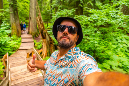 Happy tourist wearing sunglasses and bucket hat taking a selfie while hiking the beautiful giant...