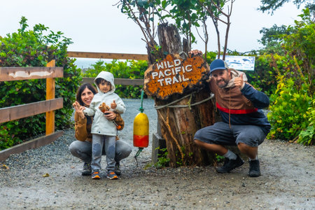 Happy family posing for a photo at the entrance of the wild pacific trail in ucluelet, british columbia, canada, enjoying a day outdoors surrounded by natureの写真素材