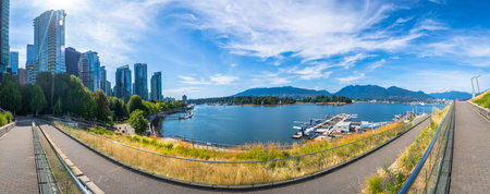 Panoramic view of Vancouver's modern skyline rising above a picturesque waterfront, showcasing lush...