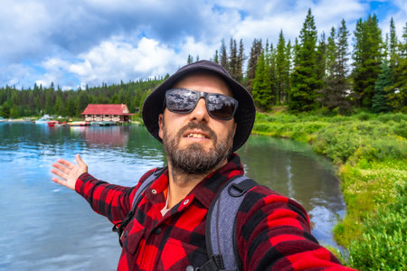 Happy tourist showing with open arms the beautiful maligne lake with the boathouse at jasper...