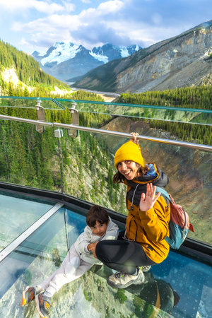 Mother and child waving from the glass platform of the glacier skywalk, enjoying the stunning panorama of the sunwapta valley and the canadian rockies in jasper national park, alberta, canadaの写真素材