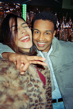 Diverse friends embracing and smiling widely, having a good time at a party or nightlife event,...