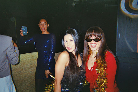 Young women celebrating and having fun in a nightclub, capturing moments with a phone, featuring a vintage retro disco vibe and flash photography effectの写真素材