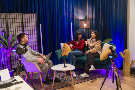 Young multiethnic creators collaborating on a podcast and social media video in a modern studio with cameras, microphones, lighting and casual, professional production setupの写真素材