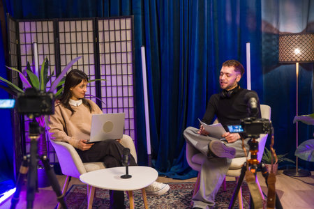 Content creators recording a video podcast or online interview in a broadcast studio, engaging with equipment for live streaming and social media production from homeの写真素材