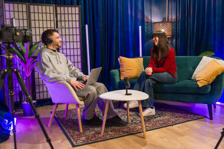 Diverse young content creators recording a podcast or social media video, sitting in a modern studio...