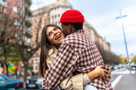 Young diverse couple embracing and laughing together on an urban street, sharing a moment of genuine happiness and showing affection while dating in the cityの写真素材