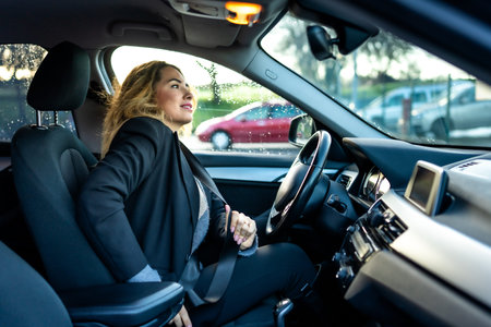 Woman in business attire buckling her seat belt in a modern car interior, prioritizing safety and...