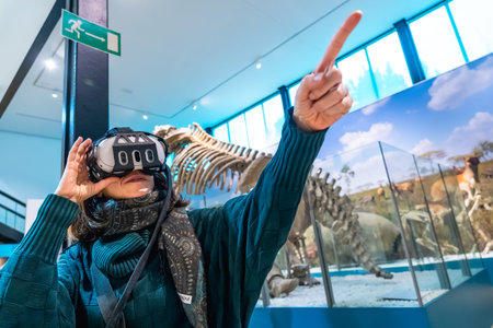 Woman wearing a virtual reality headset and pointing upward, interacting with an immersive...