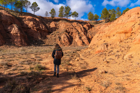 Woman with a backpack hiking through the dry, eroded landscape of las arcillas natural park in...