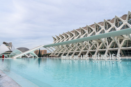 The museu de les ciencies principle building stands prominently against a cloudy sky, reflecting in...