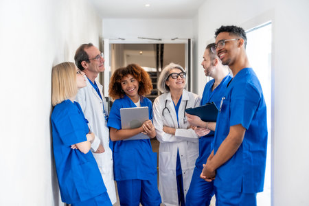 Happy multiethnic medical team of doctors and nurses in scrubs and lab coats standing in a clinic...