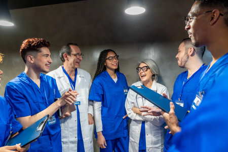 Diverse group of healthcare professionals laughing and discussing during a break, depicting teamwork, communication, and a positive working environment in medicineの写真素材