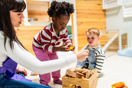 Daycare teacher interacting with diverse children on the floor, engaging in creative playtime with wooden construction blocks and colorful toys in a modern classroom