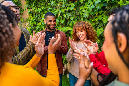 Diverse people clapping and smiling in a group therapy session, celebrating achievement and providing mutual encouragement in a supportive, inclusive outdoor setting