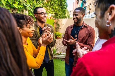 Diverse friends clapping and smiling in an outdoor group therapy circle, sharing support, empathy and connection in a sunny backyard wellness session for mental health