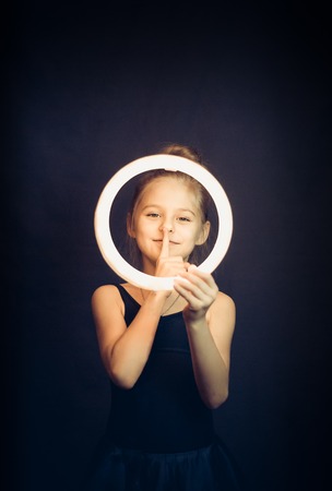 Beautiful young girl gymnast holding a glowing circle and making quiet gesture SONY DSLの写真素材